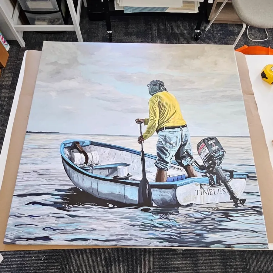 A stretched canvas of two fishermen in a small boat, resting on the studio floor.