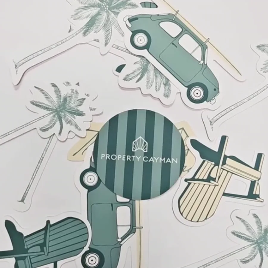 Die-cut vinyl stickers of palm trees, a vintage car carrying a surfboard and beach chairs, with a round striped logo sticker.