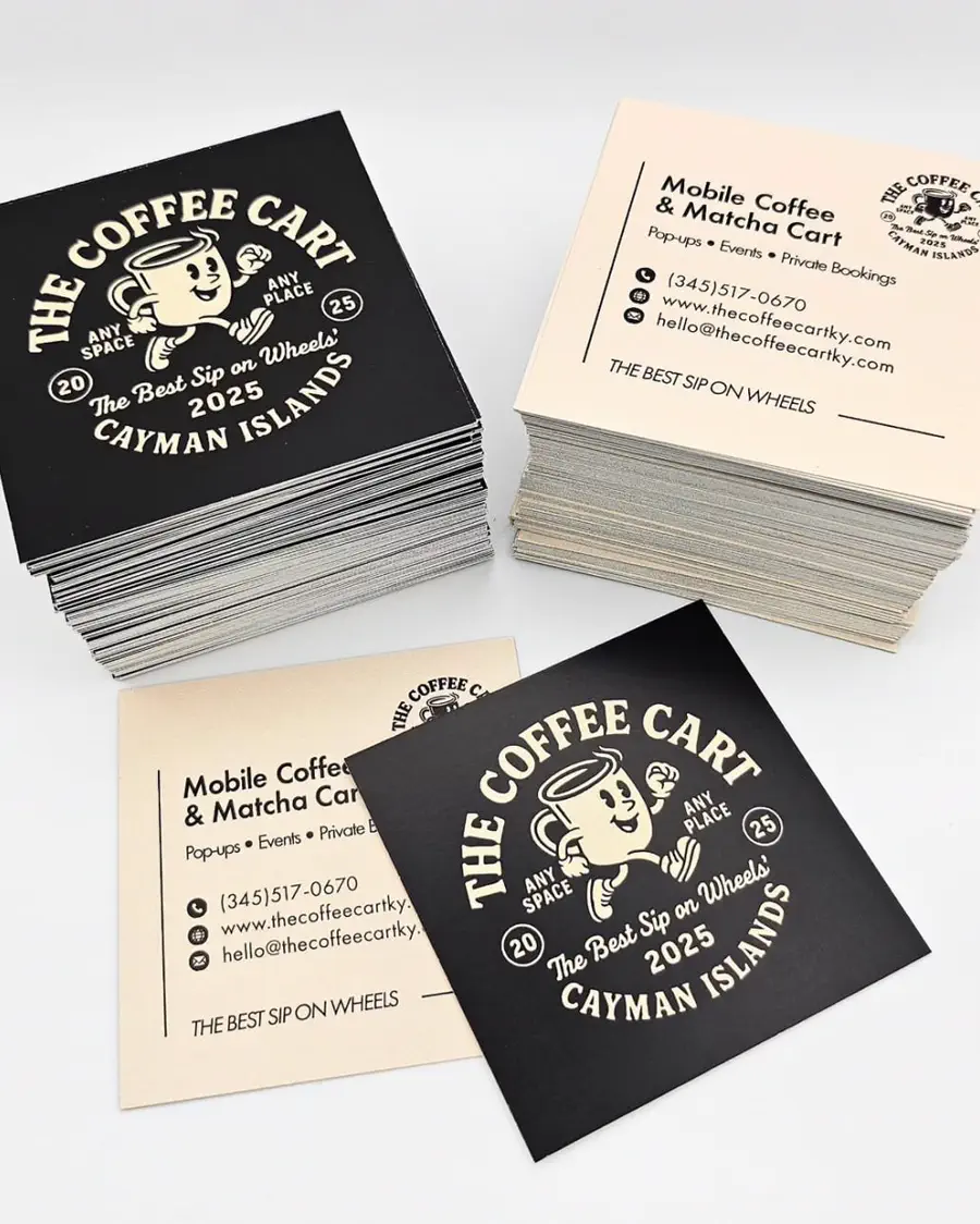 Two stacks of square business cards, one black and one cream, showing a retro running coffee-cup mascot.