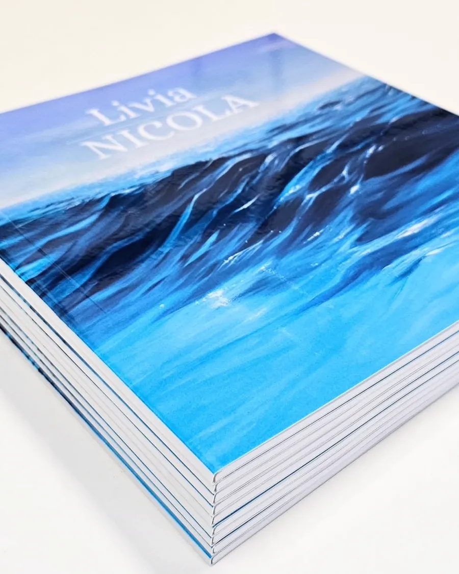 A stack of softcover books with an ocean photograph wrapping the cover.