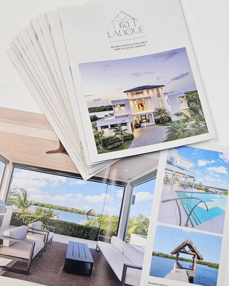 A fanned stack of property brochures showing interiors and a pool terrace.