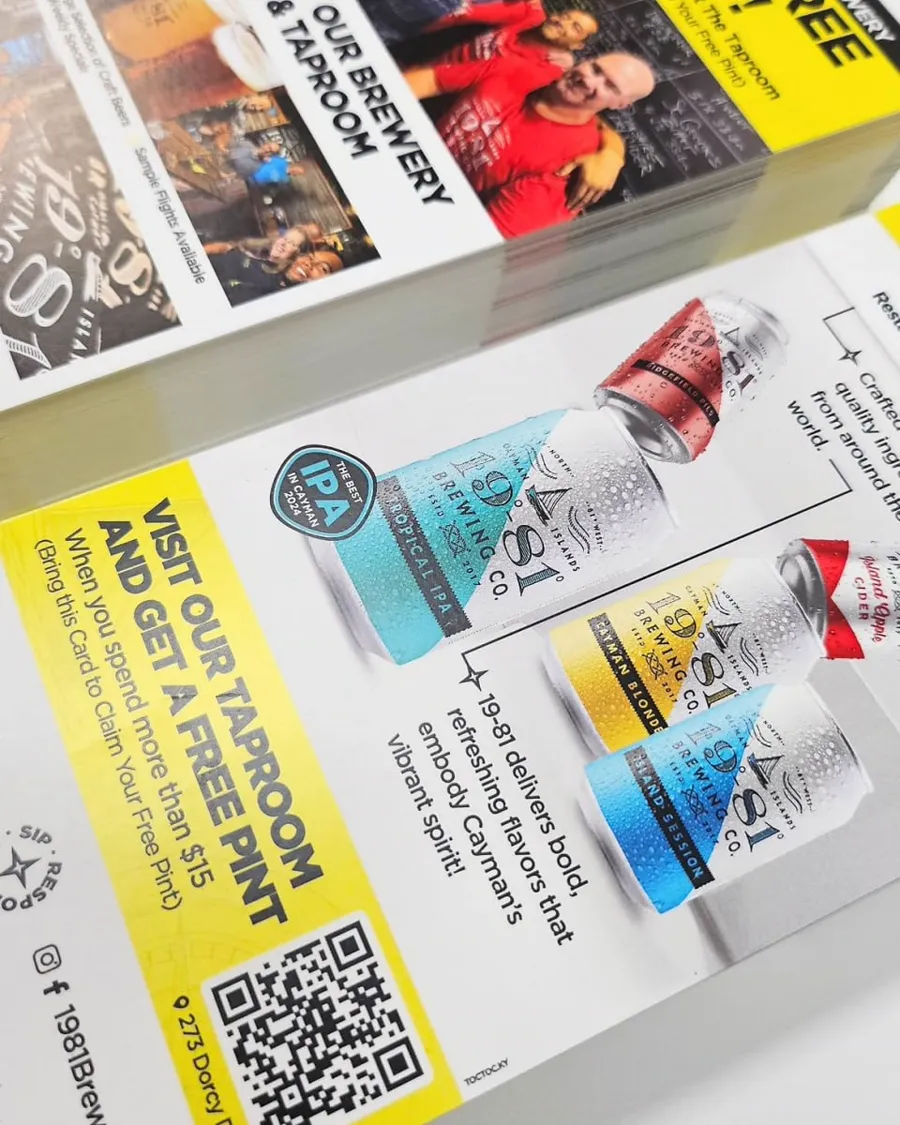 A yellow and white promotional flyer with a QR code, resting on printed material.