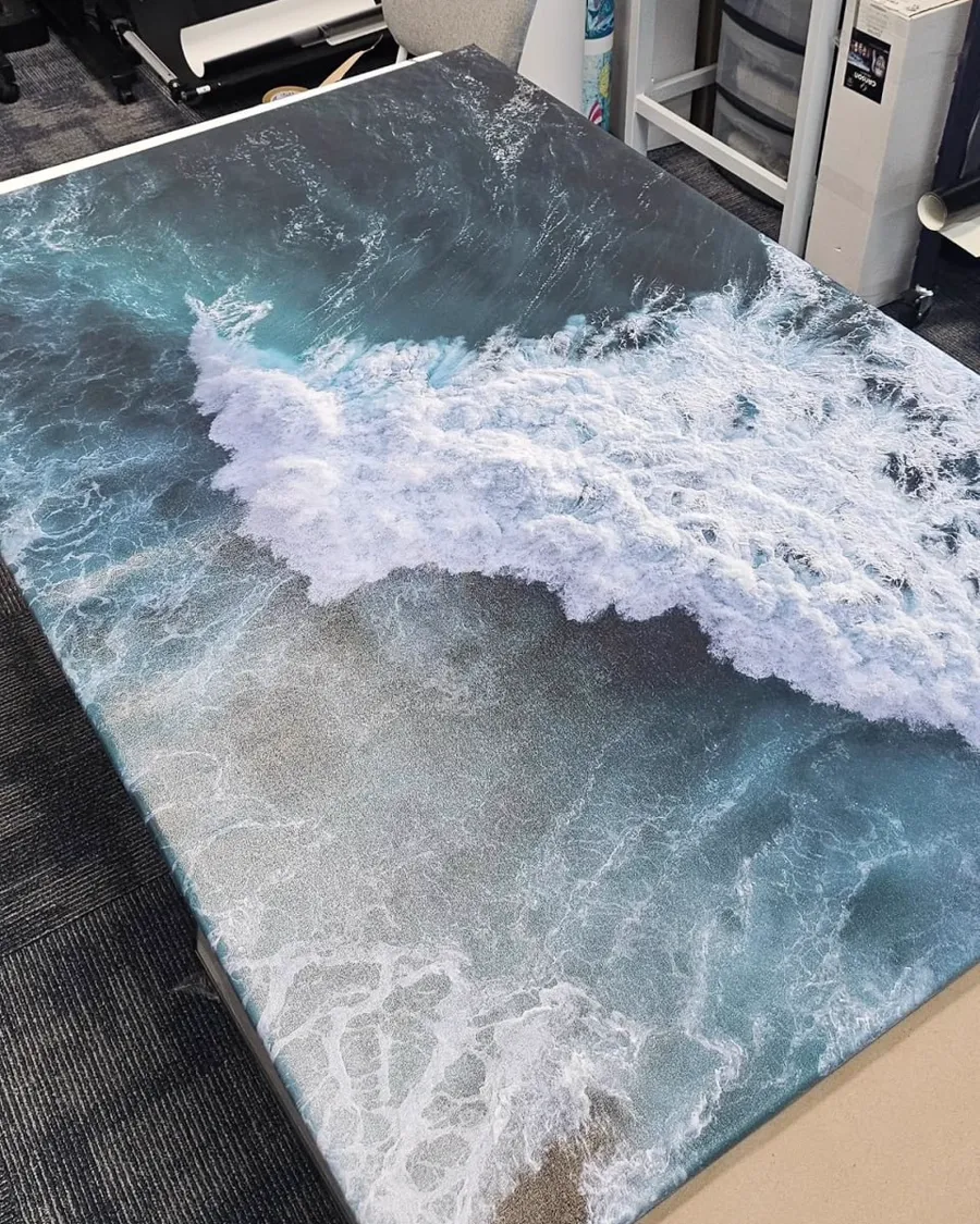 A large canvas of a breaking wave laid out flat after printing.